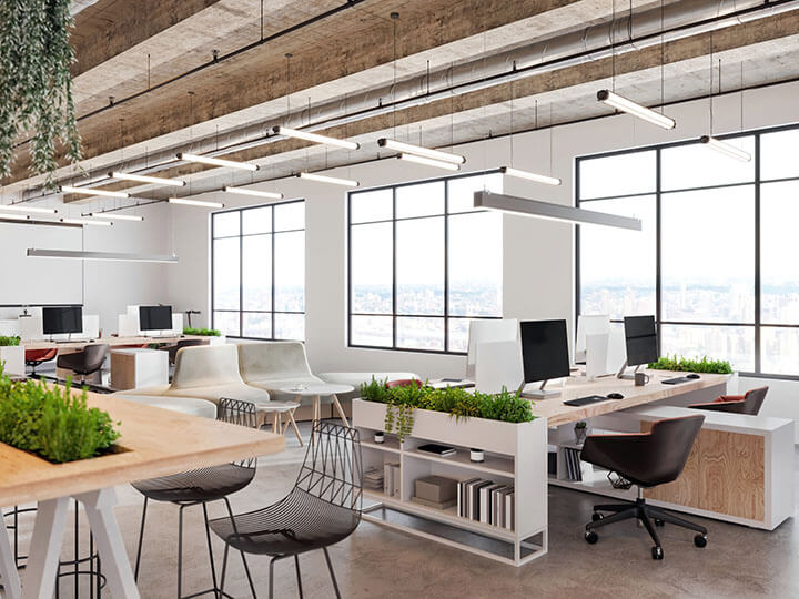 Rendered image of modern office space with table and stools, desks, computers, pendant lamps, and large windows looking over a city landscape